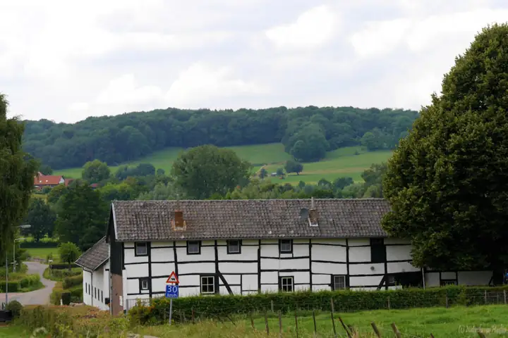 Schwarz-weißer Fachwerkhof der Ferienwohnung Hupperetz vor den Hügeln